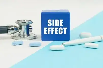 Medical concept. On a white and blue surface are pills, a stethoscope, a pen and a cube with the inscription - SIDE EFFECT
