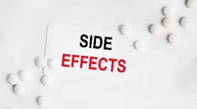 Side effects in black and red on white paper next to several white pills